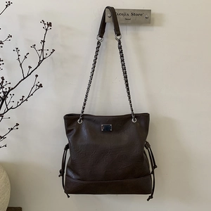 Détail du sac cabas marron vintage avec bandoulière chaîne et texture cuir mat