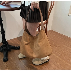 Detail of vintage brown suede hobo bag featuring wide shoulder strap and stitched edges