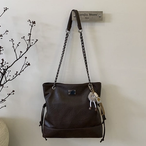 Détail du sac cabas marron foncé avec bandoulière chaîne et pendentif monstre en peluche