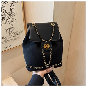 Detail of black suede bucket backpack featuring gold chain and turn-lock closure