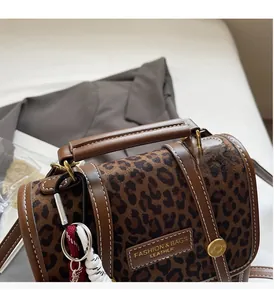 Detail of leopard print handbag with wide leather handle and stylish woven pendant