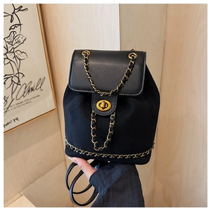 Detail of black suede bucket backpack with gold chain trim and turn-lock closure