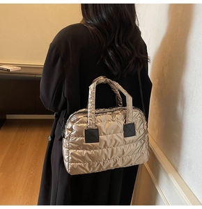 Détail du sac fourre-tout matelassé doré champagne avec texture rembourrée et patch noir