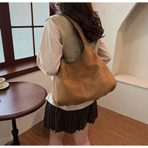 Brown suede hobo shoulder bag with vertical stitching shown in a stylish lifestyle setting