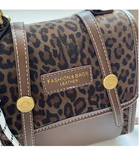 Detail of leopard print fabric with brown leather trim and white stitching on bag