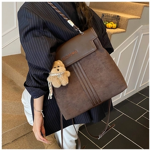 Detail view of dark brown vintage faux suede backpack with cute teddy bear charm