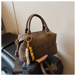Close-up of vintage brown boston bag featuring beaded zipper pull and embossed texture