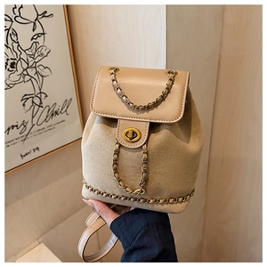 Detailed close-up of the beige bucket backpack with gold twist lock and woven chain strap
