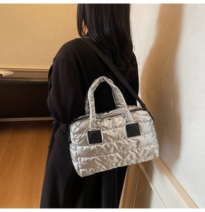 Vue détaillée du sac cabas argenté matelassé avec texture métallique et bandoulière noire