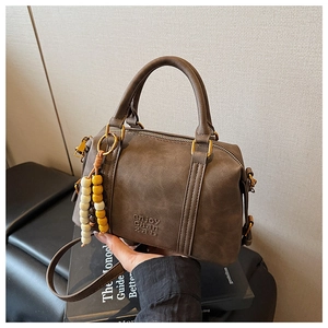 Detail of vintage mocha Boston bag with matte leather texture and beaded charm