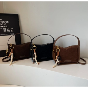 Detailed view of suede tote bags in coffee, black and tan colors with beaded tassels