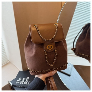 Detail of vintage brown suede backpack with gold chain straps and metal twist lock