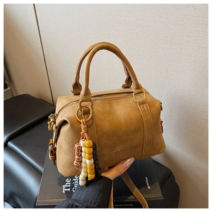 Detail of brown suede Boston bag with colorful bead charm and enjoy Chan embossing