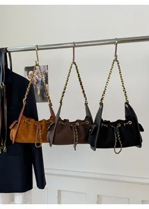 Detail of suede bucket bags with quilted patterns, chain straps and drawstring closures