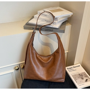 Detailed view of caramel brown soft leather tote bag with silver zipper and long strap