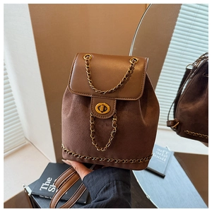 Detail of a brown patchwork backpack featuring a metal chain and golden swivel lock