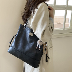 Détail du sac cabas en cuir noir avec chaîne argentée et pendentif en peluche mignon