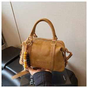Close-up of brown suede Boston bag with gold hardware and colorful beaded charm