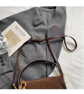 Detail of adjustable leather strap and brown suede texture on this retro shoulder bag