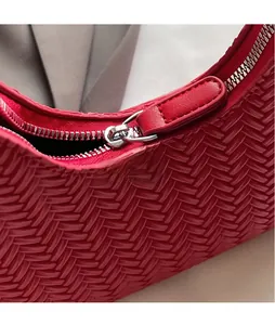 Dettaglio macro della borsa in pelle intrecciata rossa con trama e cerniera d'argento