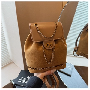 Detail of mini brown backpack featuring suede textures and gold chain accents