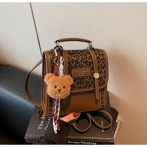 Detail of vintage brown leather backpack with leopard print and cute bear charm