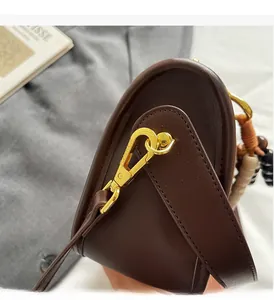 Detail of brown matte leather bag with golden metal hook and elegant texture