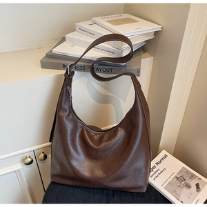 Detail of dark brown leather hobo bag showing pebbled texture and silver zipper closure