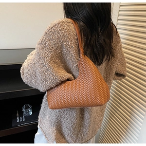 Dettaglio della borsa a mezzaluna intrecciata marrone con texture premium sulla spalla