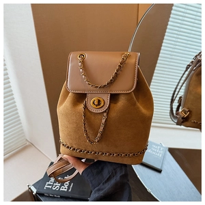 Detail of a brown suede backpack with a gold chain trim and twist-lock metal closure