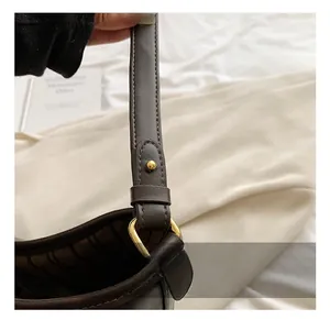 Detail view of smooth dark brown leather bucket bag featuring gold ring hardware and stitching