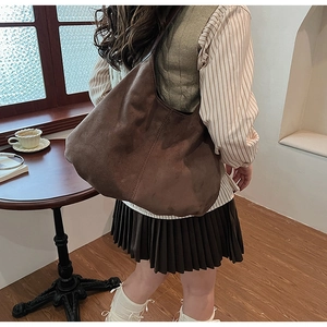 Detail of a large vintage brown suede hobo tote bag in a cozy cafe setting for women
