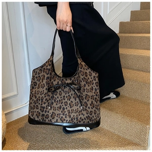 Close-up of leopard print tote bag with black leather handles and bow detail