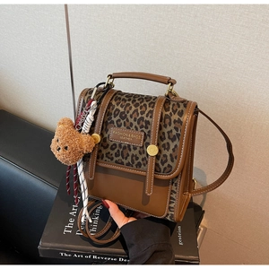 Detail of leopard print flap backpack with gold buckle and brown plush bear charm