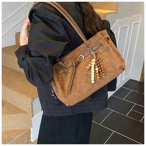 Detail of a brown matte leather tote bag with vintage wood bead fringe and tassel charm