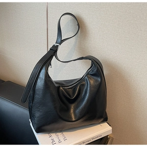Close-up of vintage black faux leather hobo bag with oily texture and silver hardware details