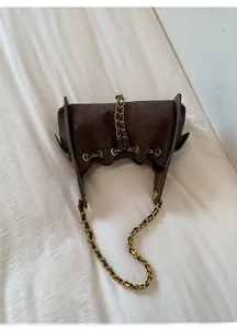 Close-up of brown suede bucket bag with quilted patterns and golden chain strap