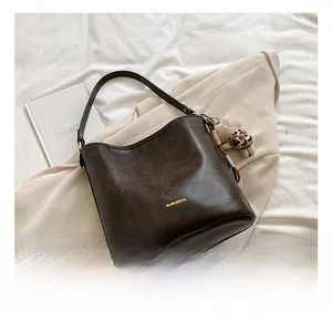 Close-up of vintage brown hobo bag with textured finish and cute bear charm on soft fabric