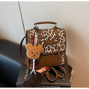 Detail of vintage brown backpack with leopard print panels and plush bear charm
