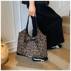 Detailed side view of a leopard print tote bag with a black leather bow and handle