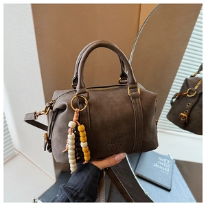 Close-up of vintage brown suede Boston bag with beaded charm and embossed text
