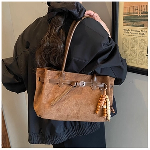 Detailed texture of brown suede tote bag featuring leather straps and vintage wood beads