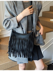 Sac seau noir pour femme avec franges longues et bandoulière réglable porté par modèle