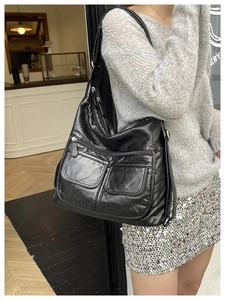 Close-up of a black multi-pocket shoulder bag in soft leather with utility style details