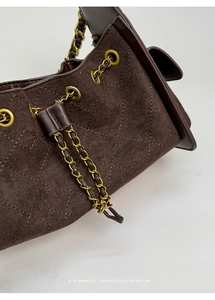 Détail du sac en daim marron avec motif matelassé et bandoulière chaîne dorée