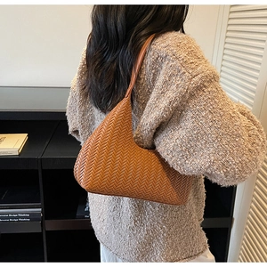 Dettaglio ravvicinato della trama intrecciata marrone della borsa Hobo portata a spalla