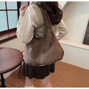 Close-up of a large brown vintage suede hobo bag on shoulder in a retro interior