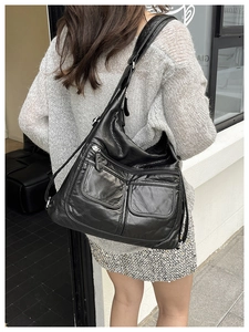 Detail showing back view of large black multi-pocket crossbody bag with soft faux leather