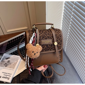 Detail of leopard print canvas backpack with brown leather trim and cute bear charm