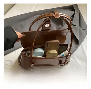 Interior view of brown pleated baguette bag showing capacity for phone and cosmetics